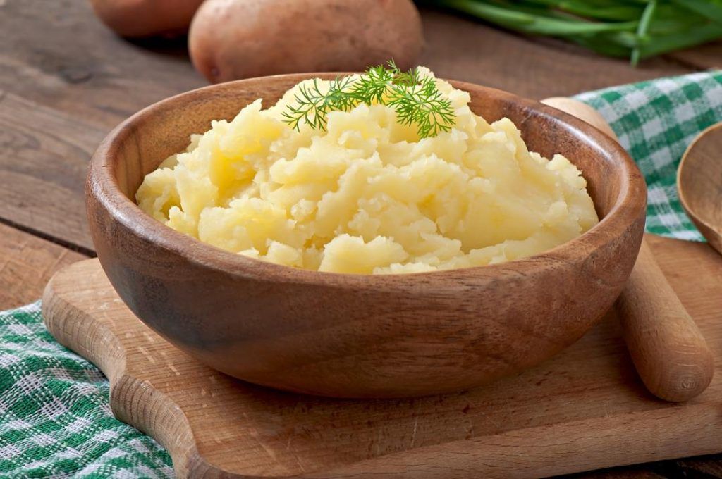A bowl of golden clarified butter (ghee) with a smooth, rich texture, commonly used in South Asian cooking.